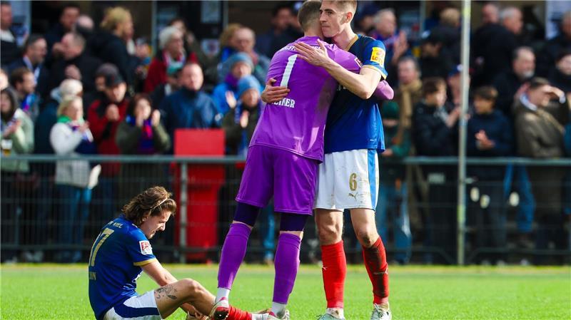 Kiels Torwart Timon Weiner (M) und Kiels Marko Ivezic umarmen sich.