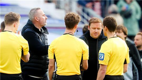 Kiels Trainer Tim Walter (2.v.l.) und Kiels Geschäftsführer Sport Olaf Rebbe (2.v.r.) unterhalten sich mit dem Schiedsrichtergespann.