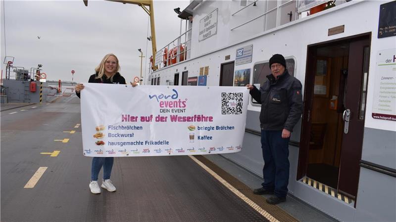 An der Weser gibt es endlich wieder einen Fähr-Kiosk Kiki Koopmann macht mit Kassierer Bernd Jürgens Werbung für den neuen Kiosk auf der Fähre. Foto: Jan Iven