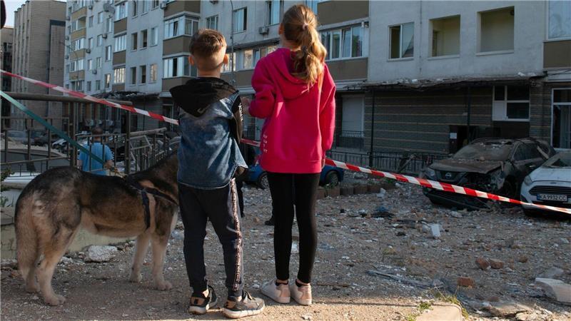Kinder blicken auf stark beschädigte Gebäude, die bei einem russischen Luftangriff auf die ukrainische Hauptstadt beschädigt wurden.