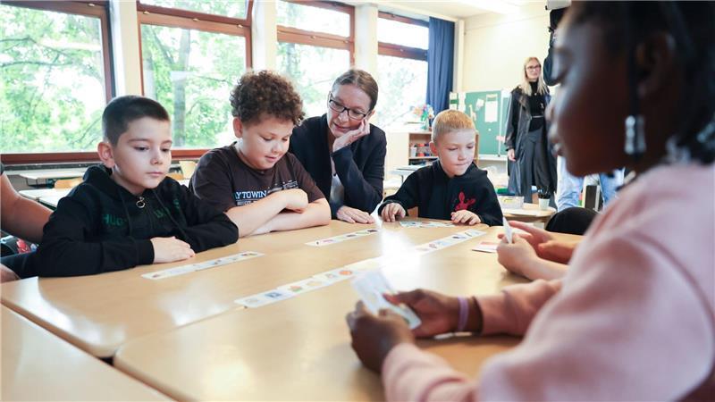 Kinder einer Hamburger Grundschule und Schulsenatorin Bekeris (SPD) schauen auf Karten. 