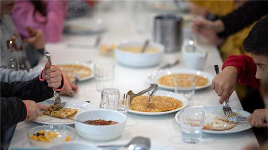 Kinder essen in der Kantine einer Grundschule Mittag.