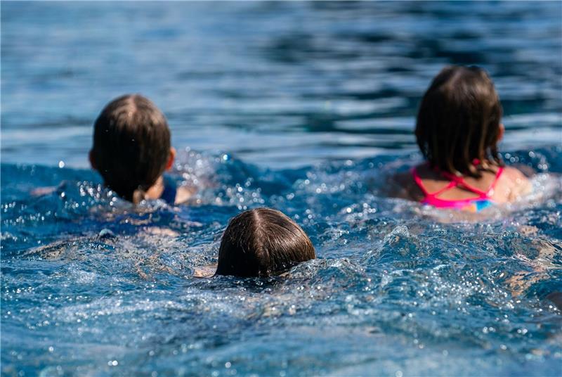 Kinder schwimmen in einem Freibad.