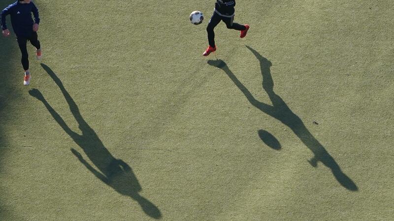 Kinder spielen auf einem Kunstrasenplatz Fußball.