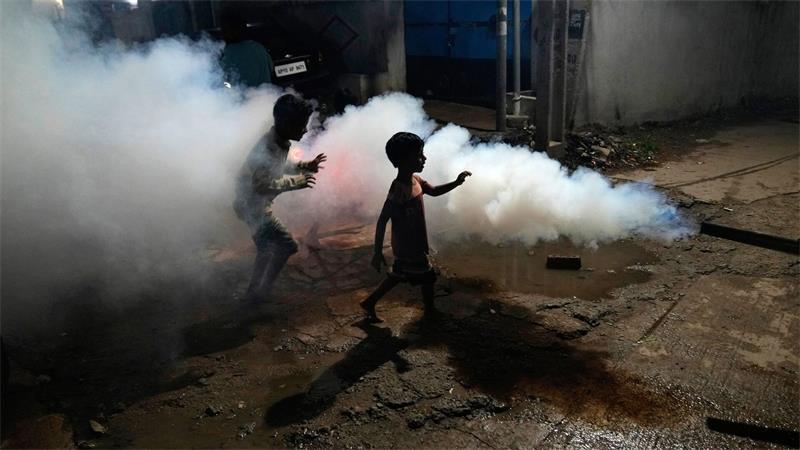 Kinder spielen inmitten der Dämpfe, die entstehen, als ein Mitarbeiter der Stadtverwaltung von Hyderabad ein Wohngebiet ausräuchert, um die Ausbreitung von durch Mücken übertragenen Krankheiten zu verhindern.