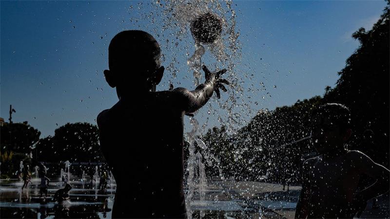Kinder spielen mit einem Ball in einem Springbrunnen in Nizza.