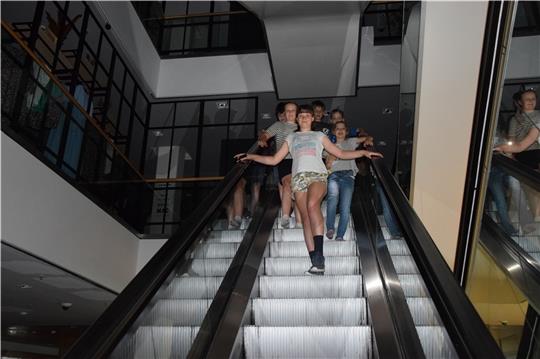 Kinder steigen die nach Ladenschluss stillstehende Rolltreppe herab.