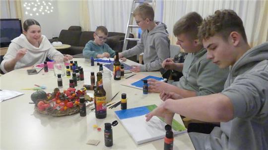 Kinder und Jugendliche aus den Elbstromdörfern malen hier gerade Acrylbilder, um die Wände des Jugendtreffs damit zu dekorieren. Vorne rechts Lauren, der zu den Stammbesuchern gehört.