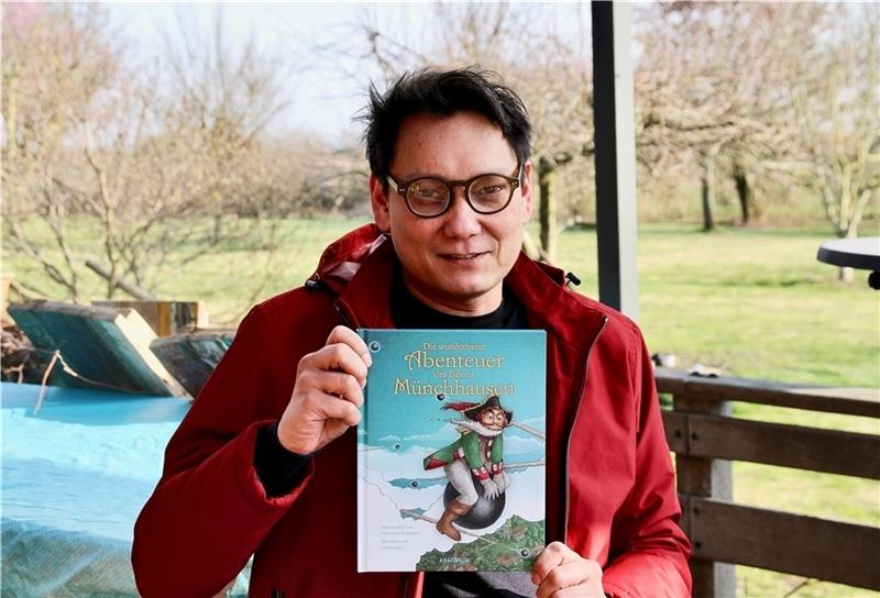 Kinderbuch-Illustrator Reiner Sprenger aus Moorende („Lesprenger“) hält das Münchhausen-Buch in seinen Händen. Foto: Richter