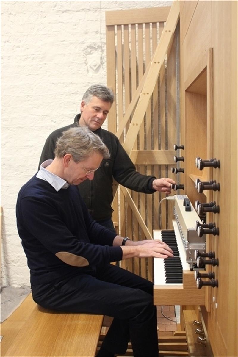 Kirchenmusikdirektor Hauke Ramm spielt auf der neuen Orgel, während Orgelbauer Jens Steinhoff eines der Register zieht.
