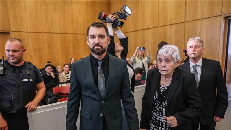 Klägerin Rita M. kommt mit ihrem Anwalt Daniel Kuhlmann (links) und dem zweiten Kläger Joachim Alfred Wagner (rechts) in den Gerichtssaal.