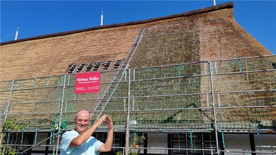 Klaus-Peter Wilkens freut sich über das Sanierungsergebnis. Er deutet mit einer Geste die Giebelform an.