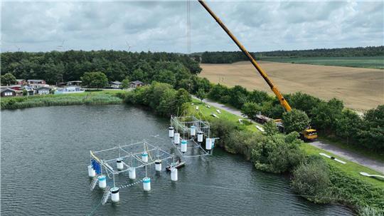 Kletterpark am Haken: Mit großem logistischen Aufwand wurde am Dienstag der vormontierte Aqua Chimp in den Kransburger See gehoben.
