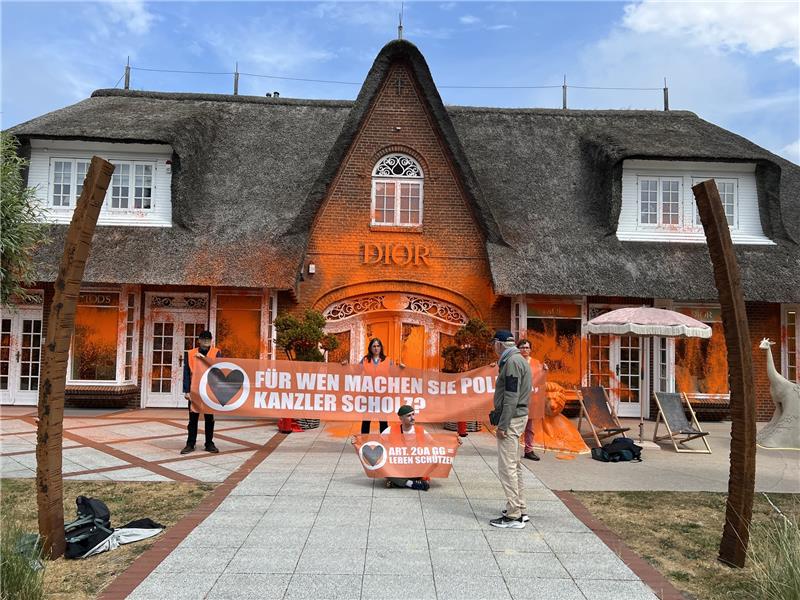Klima-Aktivisten besprühen Luxusläden auf Sylt mit Farbe Klima-Aktivisten haben sich vor einem besprühten Luxusgeschäft auf der Insel Sylt platziert. Foto: Julius-Christian Schreiner/dpa