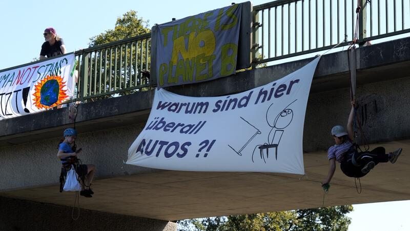 Stader Gericht lässt A27 für Protest sperren – Viel Kritik nach Unfall Klima-Aktivisten seilen sich von einer Brücke über der A27 ab und bringen Plakate an.