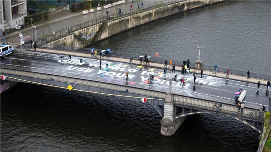 Klimaaktivisten der Bewegung Fridays for Future malen auf der Marschallbrücke in Berlin den Schriftzug „Our world is on fire - use your voice!“.
