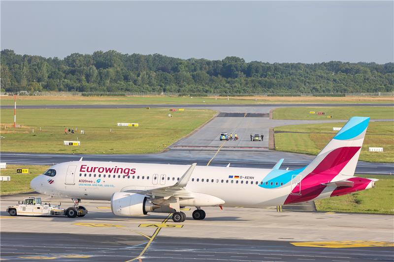 Klimaaktivisten kleben auf einem Rollfeld des Hamburger Flughafens, im Vordergrund wird eine Maschine von Eurowings umgeparkt. Foto: Bodo Marks/dpa