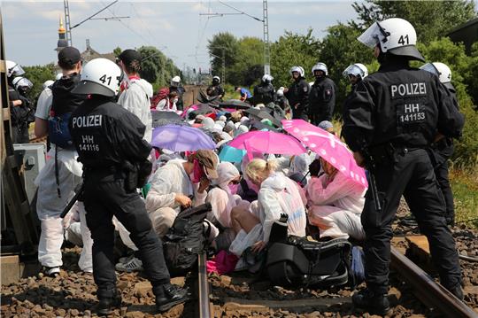 Klimaaktivisten und Teilnehmer des Klimacamps sitzen umringt von Polizei bei einem Protest auf Gleisen in Hamburg-Wilhelmsburg. Foto: Bodo Marks/dpa