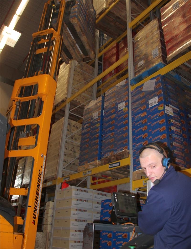 Kommissionierer Alexander Michel holt die Ware nach Roboter-Ansage aus den hohen Regalen.