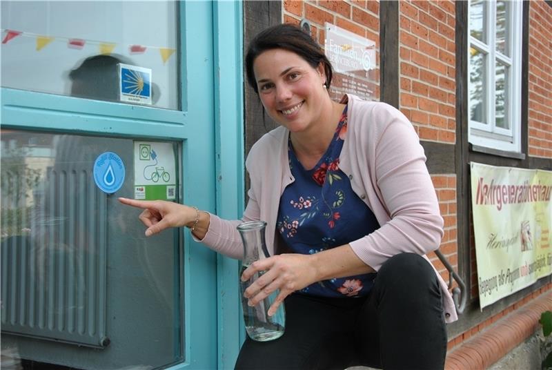 Kostenfreies Trinkwasser: Louisa Hielscher vom Freiwilligenzentrum zeigt auf den Aufkleber, der Mehrgenerationenhaus im Burgmannshof in Horneburg als eine Refill-Station ausweist. Foto: Lohmann