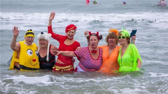 Kostümierte Eisbader vergnügen sich beim Faschingsbaden am Strand von Warnemünde in der 3,8 Grad kalten Ostsee.