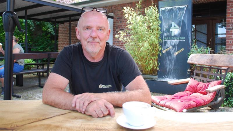Kreativer Kopf der Eisschmiede: Volker Helms im lauschigen Außenbereich mit Wasserfall und rustikalen Möbeln Marke Eigenbau.