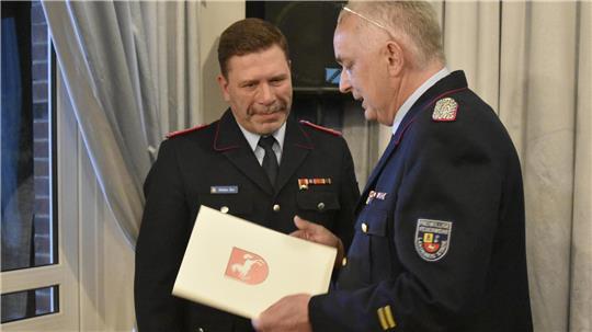 Kreisbrandmeister Thorsten Hellwege überreicht Stefan Six das Ehrenabzeichen am Bande.