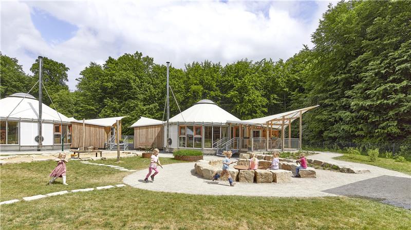 Kreisförmige Pavillons und Terrassen unter Sonnendächern: In dieser Landschaft verbringen die Kinder der Kita am Wald in Hedendorf den Tag.
