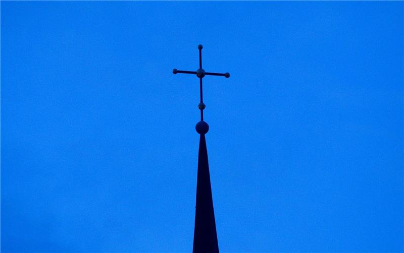 Betroffene sexueller Gewalt enttäuscht von Kirche Kreuz einer evangelisch-lutherischen Kirche in der Abenddämmerung.