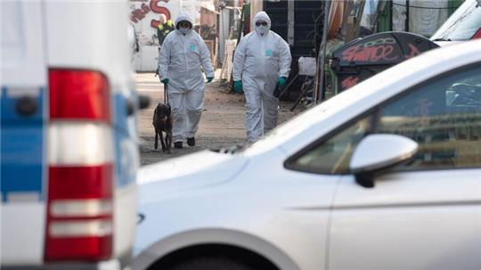 Kriminaltechniker verlassen mit einem Spürhund ein Gelände.