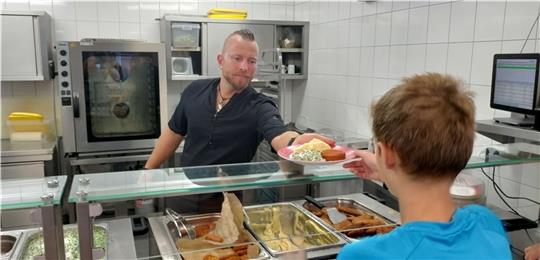 Küchenchef Dennis Perenz fasst mit an bei der Ausgabe in der Schulmensa der Oberschule. Foto: Lohmann