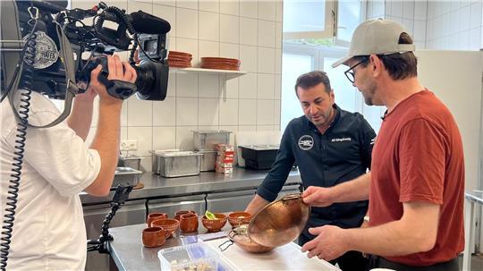 Küchenchef Ricardo (rechts) zeigt Sternekoch Ali Güngörmüs, welche Zutaten in den portugiesischen Fischeintopf Cataplana gehören.