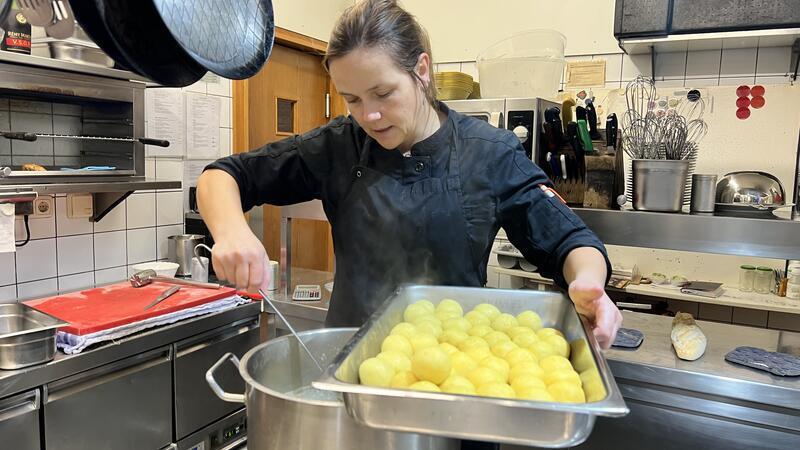 Küchenchefin Carola Staats fischt frische Kartoffelklöße aus dem Kochtopf.