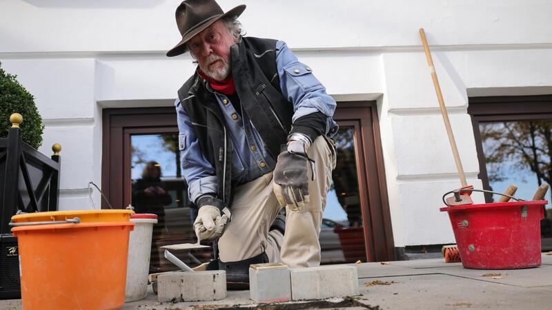7000. Stolperstein in Hamburg verlegt Künstler Gunter Demnig kniet vor dem Hotel Vier Jahreszeiten bei der Verlegung des 7000. Stolpersteins in Hamburg.