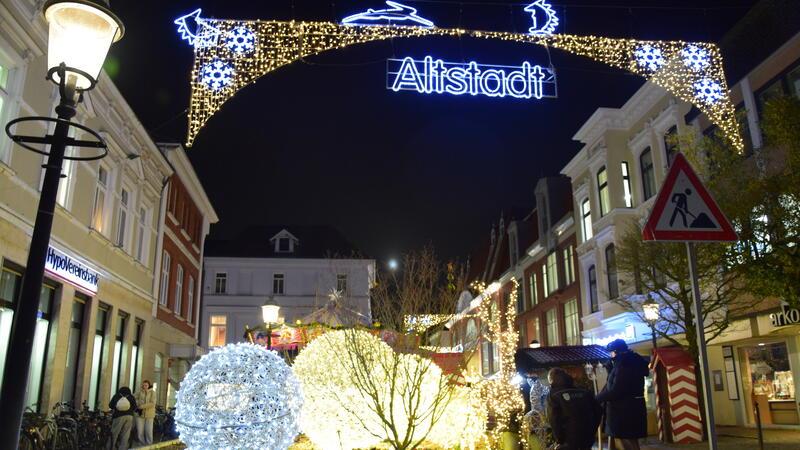 Kugelförmige Leuchten und Lichtinstallationen in Tiergestalt am Hase-und-Igel-Brunnen empfangen die Besucher am Eingang zur Altstadt. Mitarbeiter der Stadt Buxtehude arbeiten an der Stromversorgung.