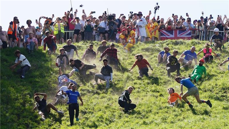Kurioser Kultlauf in Gloucestershire: Beim Käserennen 2026 rennen Männer dem rollenden Käselaib den Hügel hinunter nach.