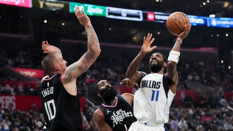 Kyrie Irving (r) von den Dallas Mavericks wirft unter dem Druck von James Harden (M) und Daniel Theis von den Los Angeles Clippers.