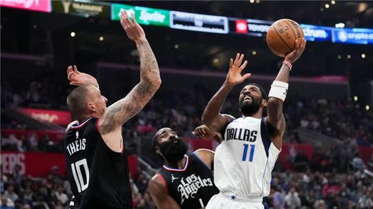 Kyrie Irving (r) von den Dallas Mavericks wirft unter dem Druck von James Harden (M) und Daniel Theis von den Los Angeles Clippers.