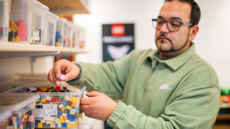 Ladeninhaber Sandro Lopes zeigt Boxen voller Legosteine.