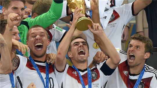  Philipp Lahm (M) aus Deutschland jubelt mit dem WM-Pokal zwischen seinen Teamkollegen Lukas Podolski (l) und Thomas Müller (r) während der Siegerehrung auf der Tribüne nach dem Sieg im FIFA Fußball-WM-Finale 2014 zwischen Deutschland und Argentinien im Estadio do Maracana. 