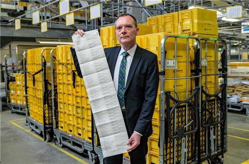 Landeswahlleiter Oliver Rudolf zeigt in einer Niederlassung der Post den 96 Zentimeter langen Wahlzettel für die Europawahl. Foto Heimken/dpa