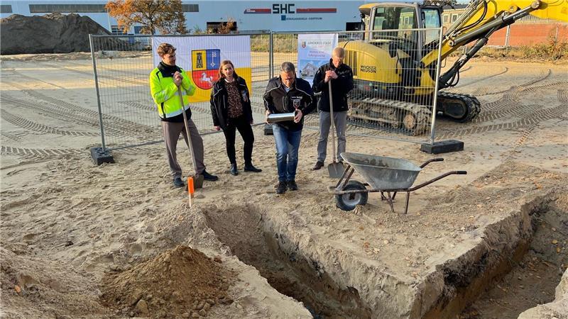 Landrat Kai Seefried (CDU) setzt die Zeitkapsel in das Fundament ein.