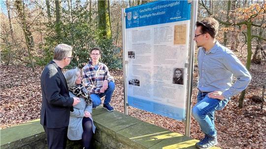 Landrat Kai Seefried und Schulpastorin Ellen Kasper tauschen sich mit Halepaghen-Schüler Sam Follmann (15) und Lehrer Duncan Kröger auf der Kriegsgräberstätte in Neukloster über die Geschichts- und Erinnerungstafel aus (von links).