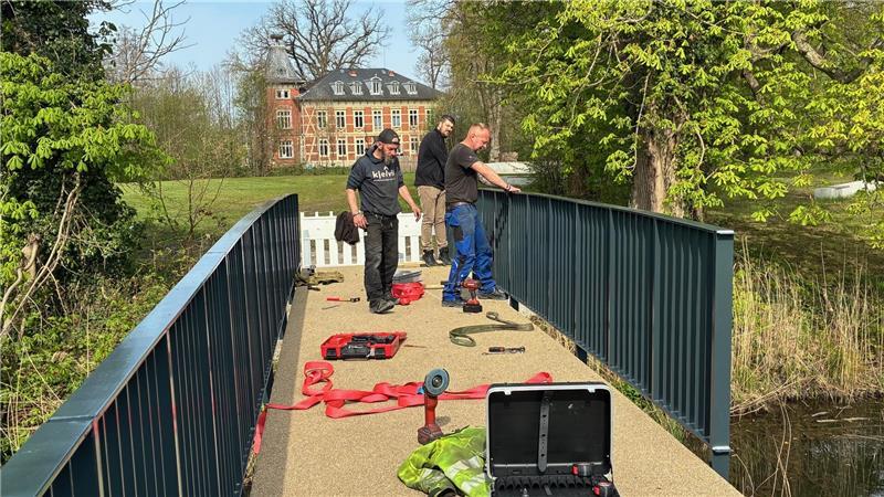 Langeheine-Metallbauer montieren das Geländer der zweiten Burginsel-Brücke, hinten ist das Horneburger Schloss zu sehen.