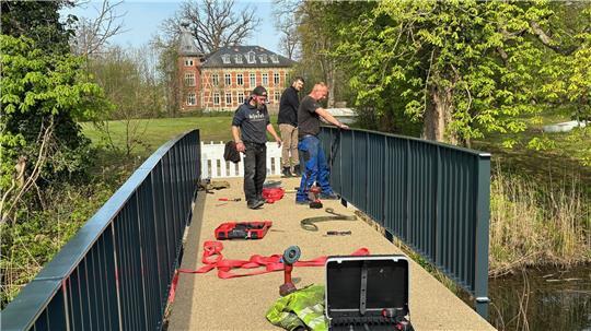 Langeheine-Metallbauer montieren das Geländer der zweiten Burginsel-Brücke, hinten ist das Horneburger Schloss zu sehen.