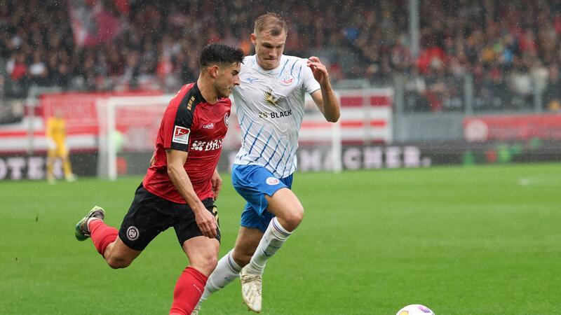 Wehen Wiesbaden mit weiterem Befreiungsschlag gegen Rostock Laufduell zwischen Robin Heußer (l) von SV Wehen Wiesbaden und Svante Ingelsson (r) von Hansa Rostock.