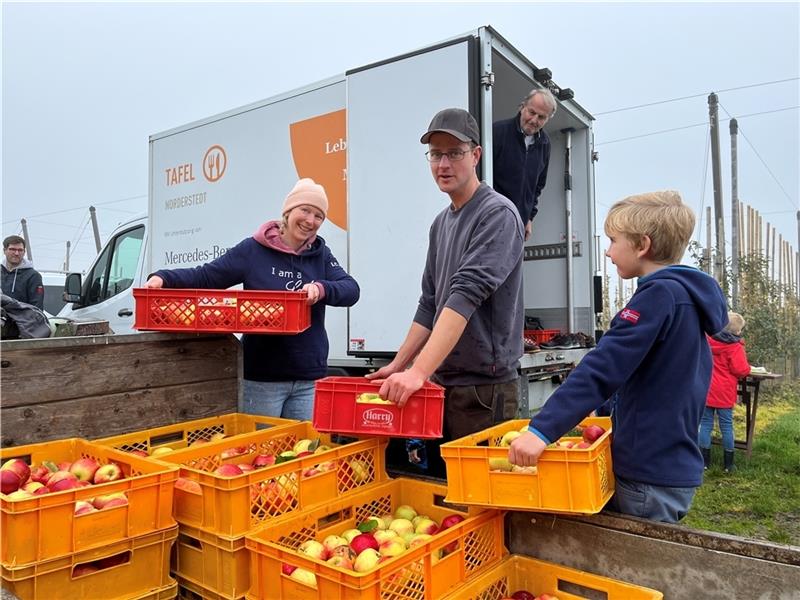 Lebensmittel-Retter: Constanze Siebert vom Ladies‘ Circle aus Norderstedt (von links) belädt mit Obstbauer Christian Plaaß aus Estebrügge und Peter Lorenz von der Tafel den Lkw mit Äpfeln, auch Malte hilft. Fotos: Vasel