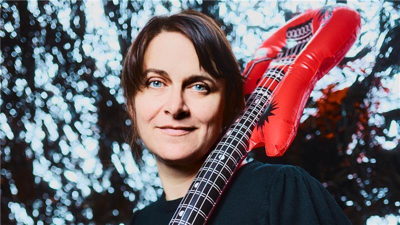 Ella Carina Werner mit einer aufblasbaren Luftgitarre über der Schuletr