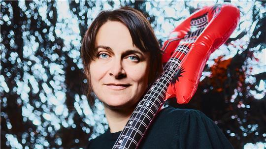 Ella Carina Werner mit einer aufblasbaren Luftgitarre über der Schuletr