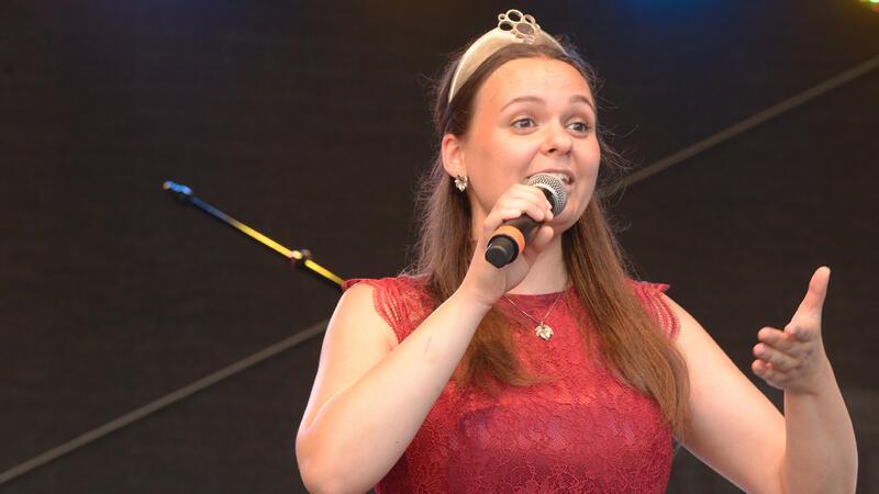 Sarah Röhl steht mit rotem Kleid und Krone auf der Bühne